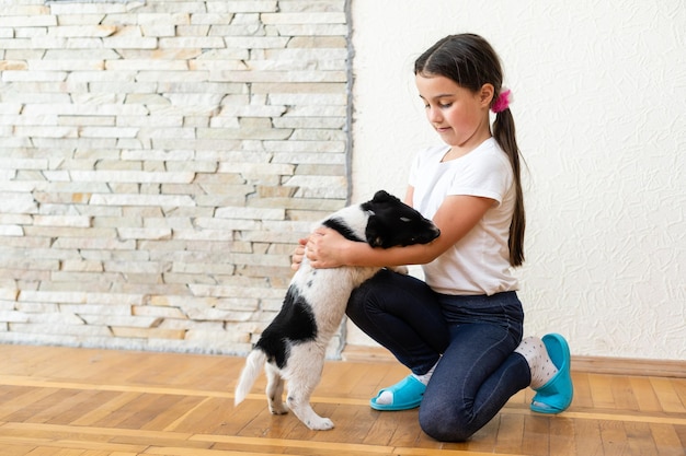 Retrato de menina feliz em casa com cachorrinho.