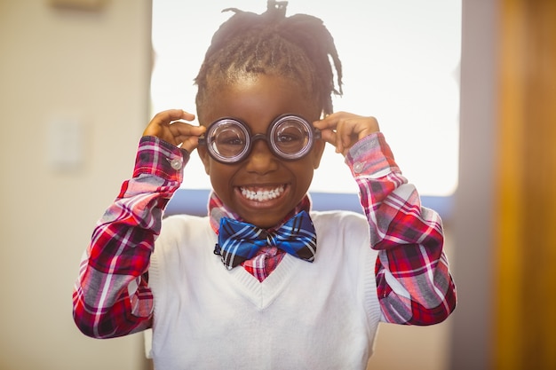 Retrato de menina feliz no espetáculo sorrindo na sala de aula