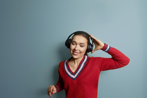 Retrato de menina feliz ouvindo música com fones de ouvido sem fio de um smartphone