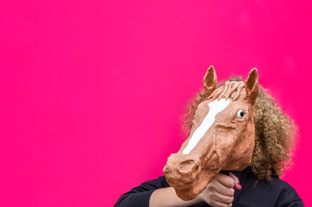 Foto retrato de menina loira encaracolada segurando o brinquedo da cabeça de cavalo