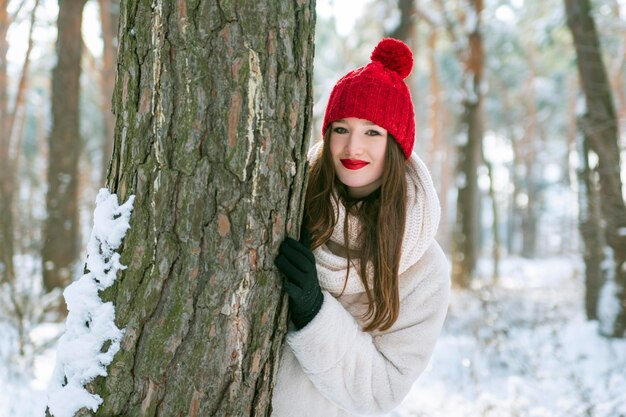 Retrato de menina morena de chapéu vermelho na floresta de inverno