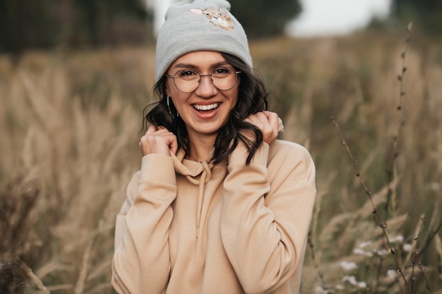 Retrato de menina morena sorridente de óculos no campo