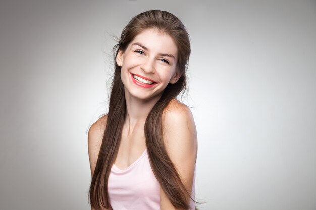 Retrato de menina morena sorridente dentuça, posando para a câmera. Tiro isolado do estúdio.