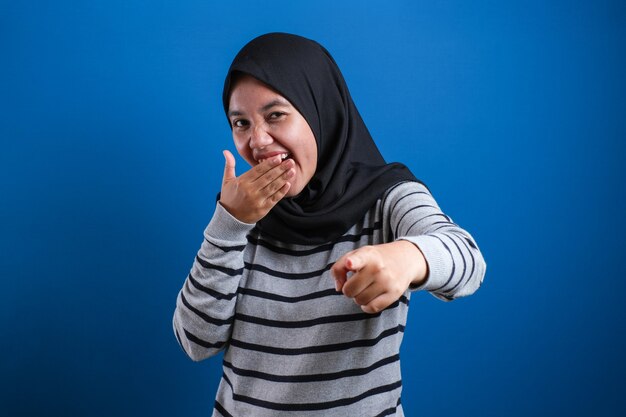 Retrato de menina muçulmana usando hijab rindo muito, expressão feliz, close-up na cabeça contra um fundo azul