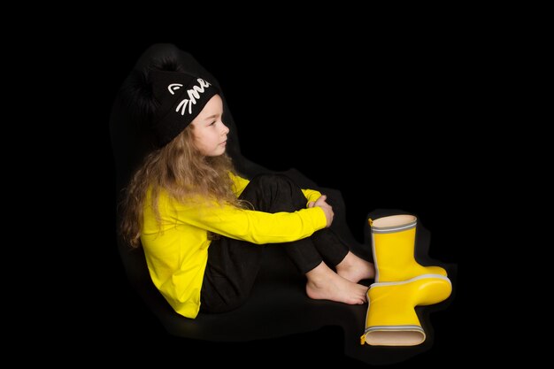 Retrato de menina muito alegre, com roupas pretas e amarelas, copie o espaço, isolado no fundo preto. Emoções infantis. Foto de alta qualidade