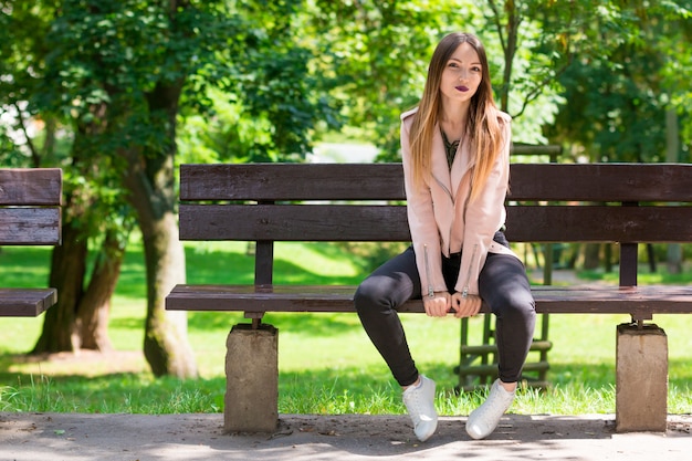 Retrato de menina na moda no banco no parque