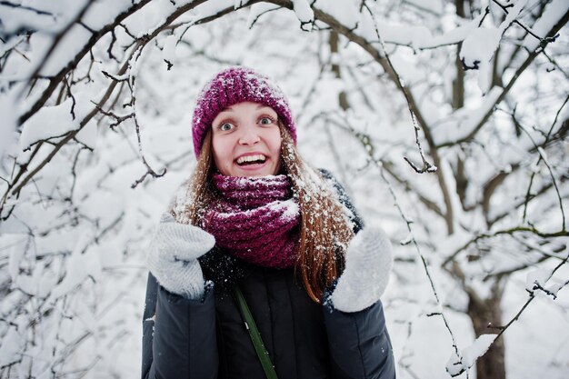 Retrato de menina no dia de inverno nevado perto de árvores cobertas de neve