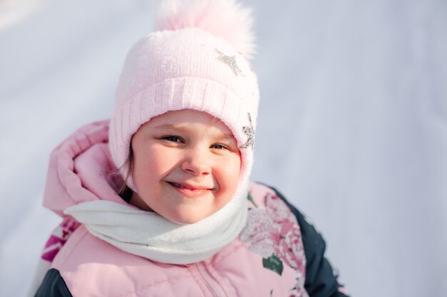 Retrato de menina no fundo do monte de neve closeup de criança feliz, sorrindo e apreciando a caminhada.