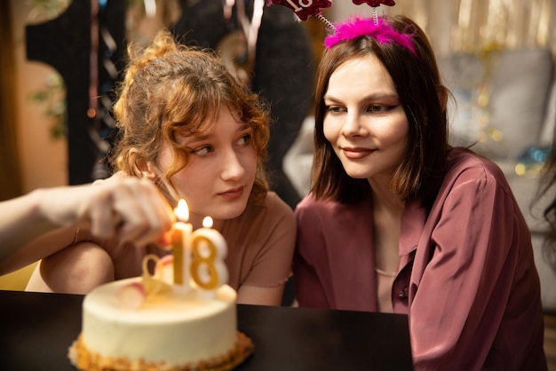 Retrato de menina olhando para o bolo de aniversário cercado por amigos na festa