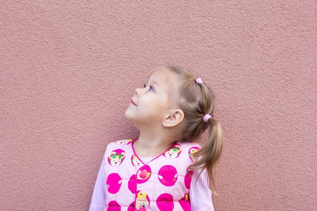 Retrato de menina olhando para o canto do tiro segurando a cabeça no fundo rosa