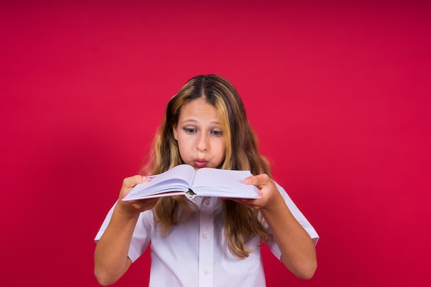 Retrato de menina positiva com notebook parece sorrindo para a criança da câmera fazendo lição de casa