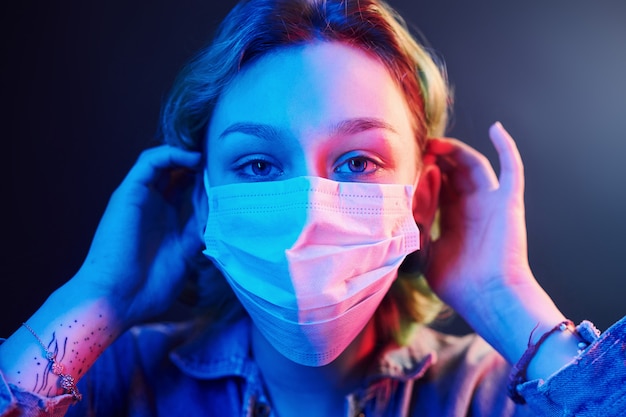 Retrato de menina que usando máscara protetora no rosto em luzes de neon