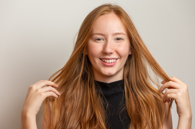 Retrato de menina ruiva alegre bonita sorrindo rindo sobre parede branca