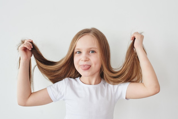 Retrato de menina segurando o cabelo nas mãos em fundo branco