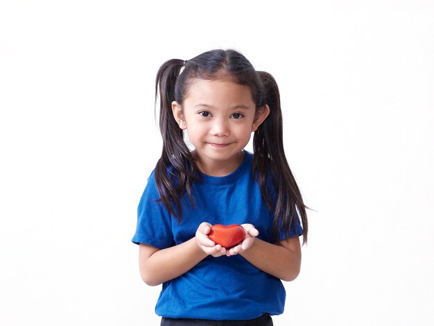 Retrato de menina segurando um coração vermelho na parede branca. Espaço para texto