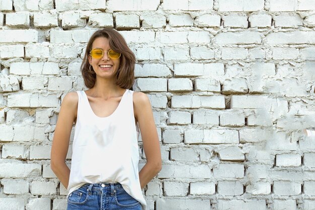 Foto retrato de menina sorridente adolescente fundo de parede de tijolo branco