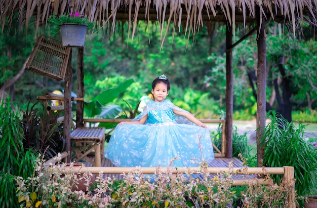 Retrato de menina sorridente bonitinha em traje de princesa em pé na cabana