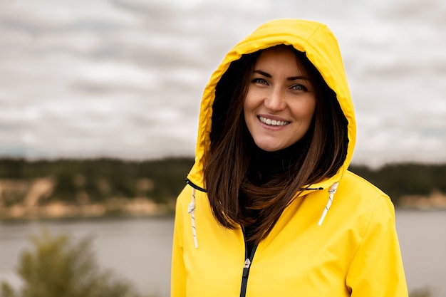 Retrato de menina sorridente com capa de chuva amarela no lago