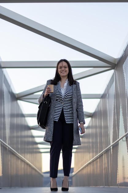 Retrato de menina sorridente com os braços cruzados em uma ponte na cidade Jovem sorridente em pé de braços cruzados em uma ponte