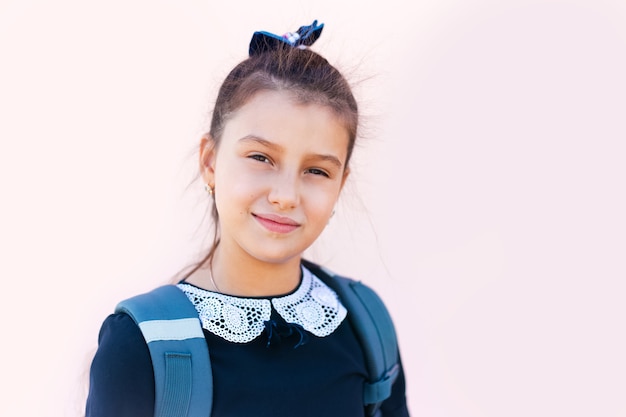 Retrato de menina sorridente da escola, na parede rosa claro.