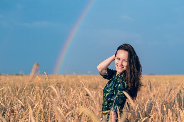 Retrato de menina sorridente no campo de trigo com espigas de ouro no arco-íris