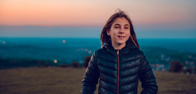 Retrato de menina vestindo jaqueta preta ao pôr do sol