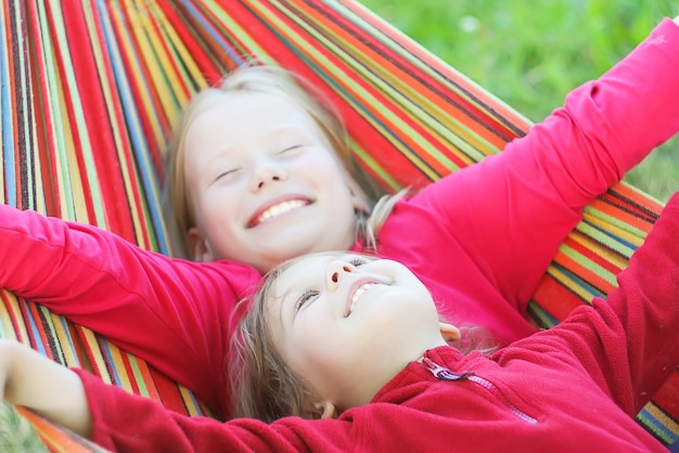 Retrato de meninas adoráveis em uma rede listrada no parque de verão