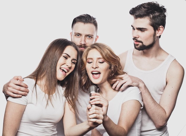 Retrato de meninas felizes e caras cantando no microfone sobre fundo branco