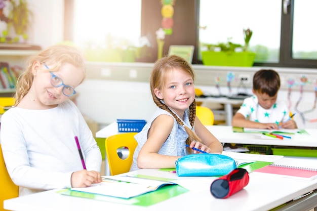 Retrato de meninas sorridente sentadas à mesa na sala de aula