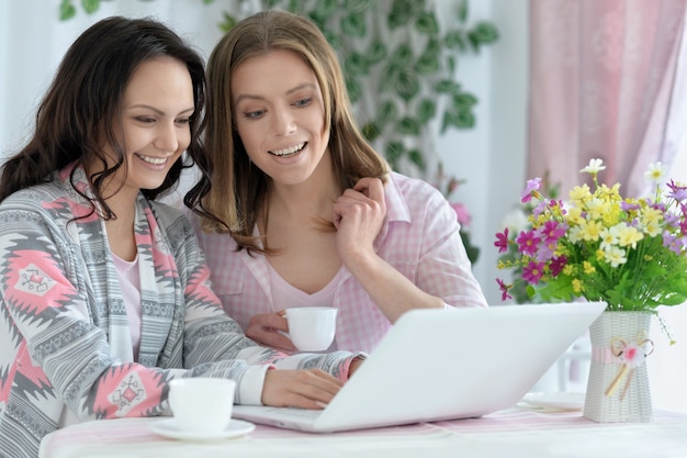 retrato de meninas tomando café ou chá com o laptop em casa