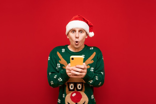 Retrato de menino adolescente com suéter de Natal segurando o telefone