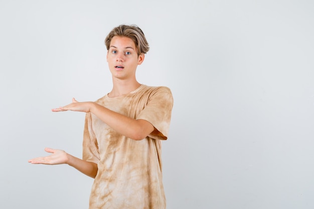 Retrato de menino adolescente mostrando sinal de tamanho na camiseta e olhando confiante para a frente