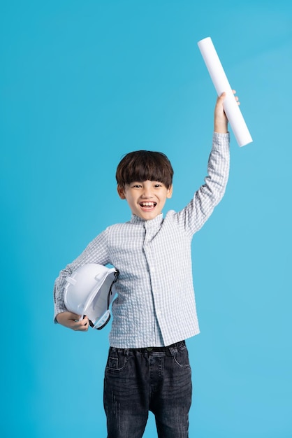 Retrato de menino asiático desempenhando o papel de engenheiro isolado em fundo azul