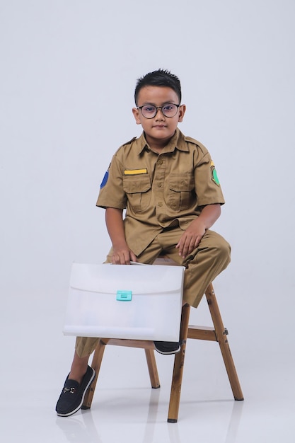 Retrato de menino asiático vestindo um uniforme cáqui do governo indonésio. Aspiração infantil como professor.