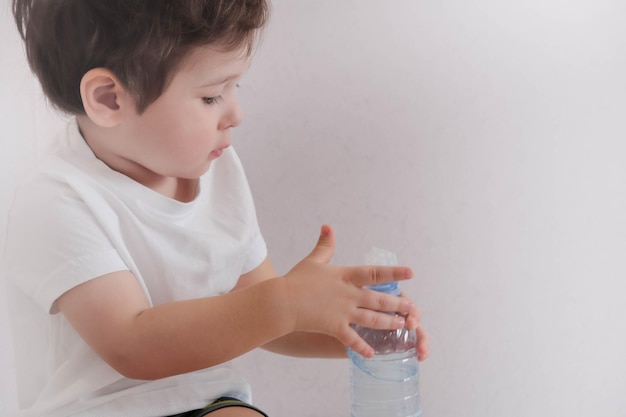 Retrato de menino bebendo copo de água bebê bebe água de uma garrafa de plástico