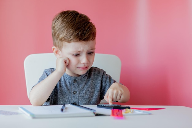 Retrato de menino bonitinho em casa fazendo lição de casa Criança concentrada escrevendo com lápis colorido dentro de casa Ensino fundamental e educação Criança aprendendo a escrever letras e números