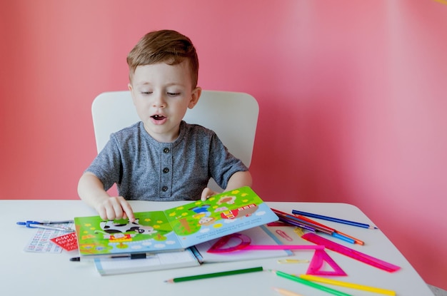 Retrato de menino bonitinho em casa fazendo lição de casa Criança concentrada escrevendo com lápis colorido dentro de casa Ensino fundamental e educação Criança aprendendo a escrever letras e números