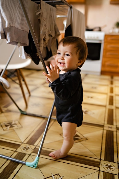Retrato de menino bonitinho no interior de casa secando roupas ajuda no trabalho doméstico