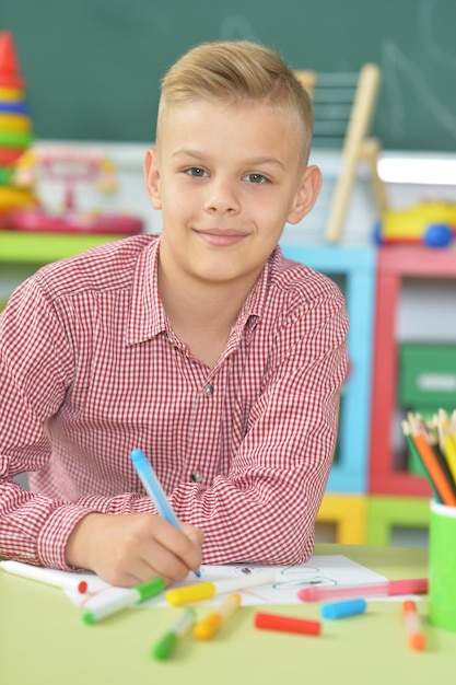 Retrato de menino bonito desenhando em sala de aula