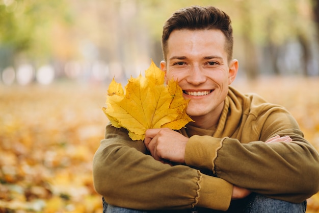 Retrato de menino bonito e feliz com um buquê de folhas amarelas sorrindo