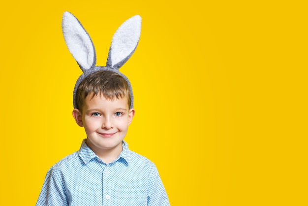 Retrato de menino bonito sorridente usando orelhas de coelhinho da Páscoa em um fundo amarelo. Copie o espaço. Feliz Páscoa. Venda de Páscoa.
