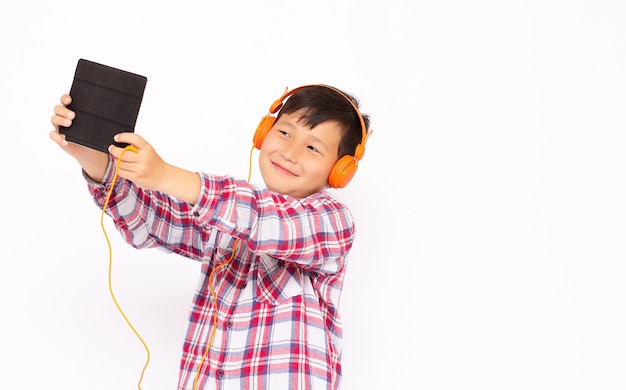 Retrato de menino brincando de tablet e usando fones de ouvido em fundo branco