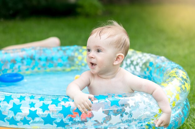 Retrato de menino brincando na piscina do jardim
