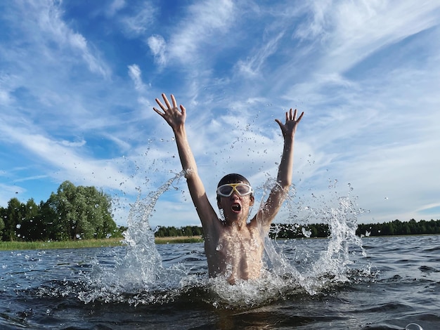 Foto retrato de menino com máscara de água com os braços levantados na água