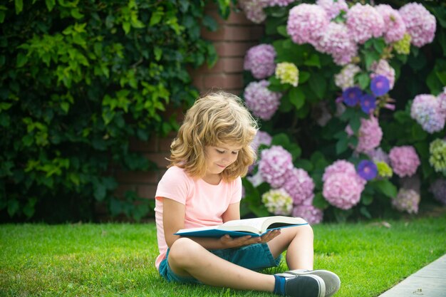 Retrato de menino criança feliz com livro no parque Educação infantil infantil Criança leu livro no jardim Trabalho de casa de férias de verão Estudante pré-escolar ao ar livre Menino bonitinho da escola primária