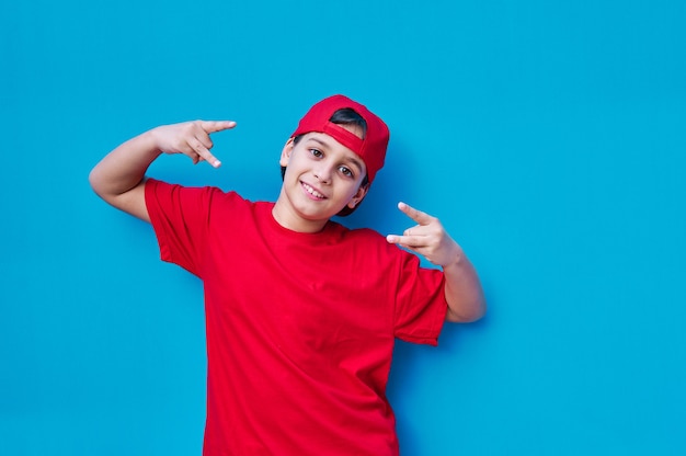 Retrato de menino de camiseta e boné vermelho colocando os chifres com os dedos