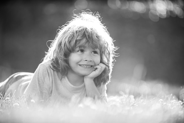 Retrato de menino deitado na grama no parque natural de verão