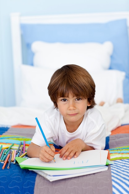 Foto retrato de menino desenhando na cama