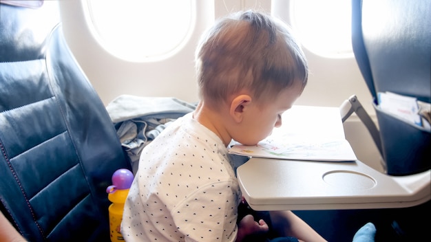 Retrato de menino entediado da criança durante o longo voo no avião.