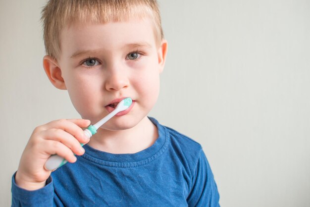 Foto retrato de menino escovando os dentes no espaço de cópia de higiene dental de fundo claro para texto